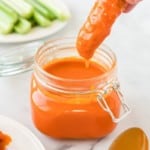 Homemade Buffalo Sauce in a mason jar with chicken tender being dipped in them