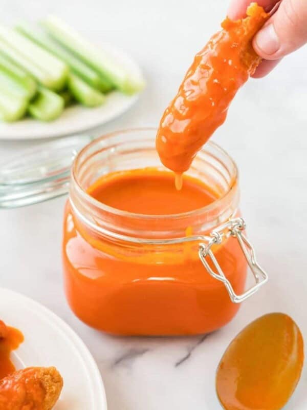 Homemade Buffalo Sauce in a mason jar with chicken tender being dipped in them