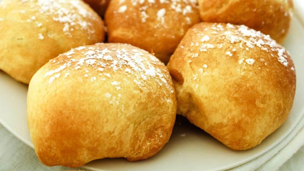 Air fried Oreos with crescent rolls close up on a white plate dusted with powdered sugar.