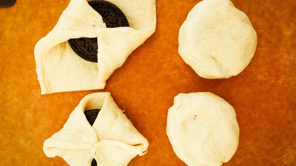 Wrapping the air fried Oreos with the crescent rolls by attaching each corner together in the middle then bunching together to close it.