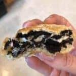 Hand holding an air fryer oreos that has been bitten into so you can see the oreo in the middle.