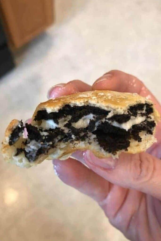 Hand holding an air fryer oreos that has been bitten into so you can see the oreo in the middle.
