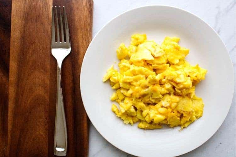 Scrambled Eggs on a white plate with fork to the side