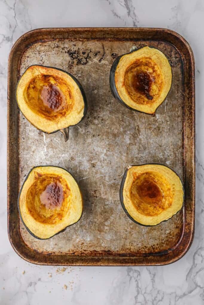 Roasted acorn squash halves on a baking sheet