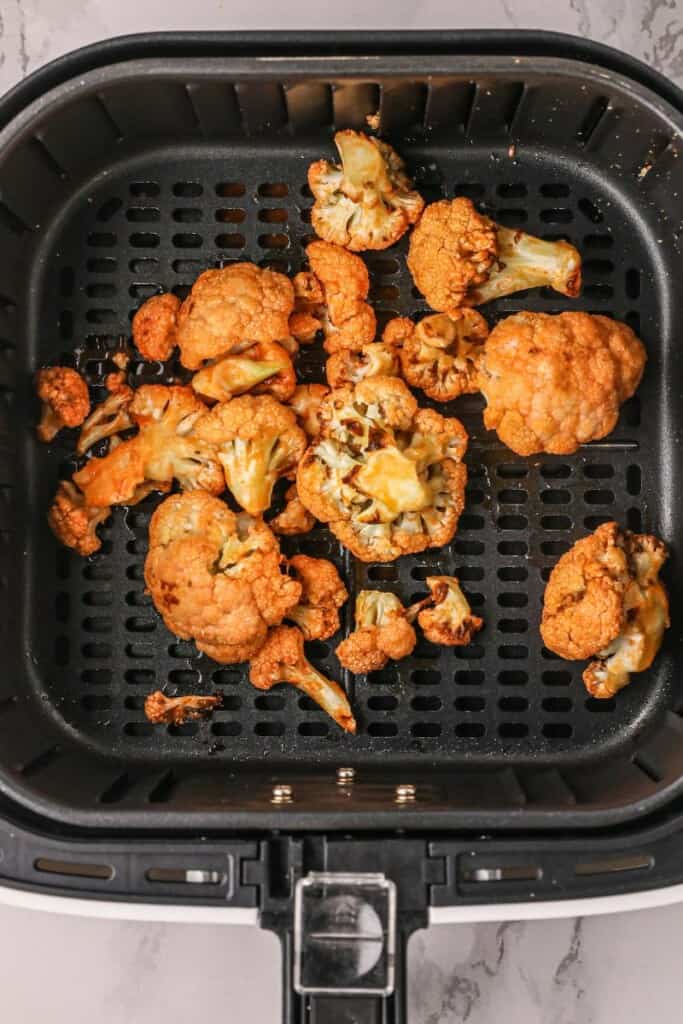 Cooked buffalo cauliflower in air fryer basket