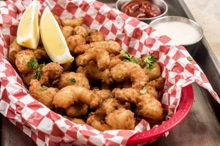 Air Fryer Popcorn Shrimp in a red basket with lemon wedges