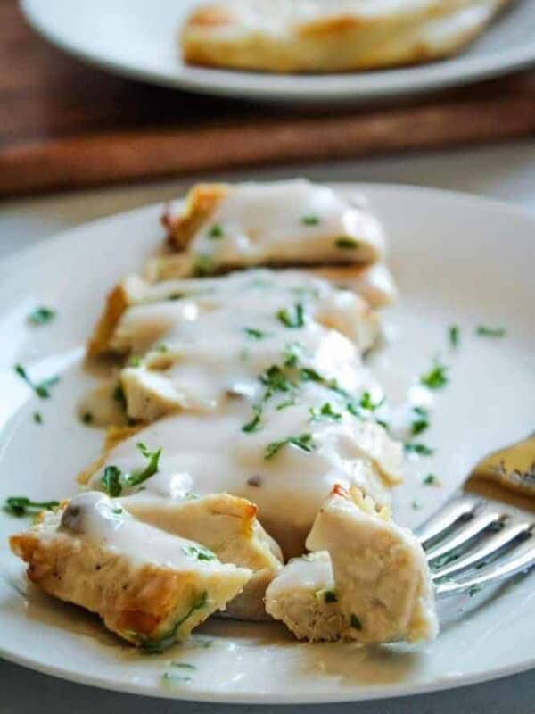 Air Fryer Turkey Cutlets covered in mushroom sauce sliced on a white plate with a fork in one piece