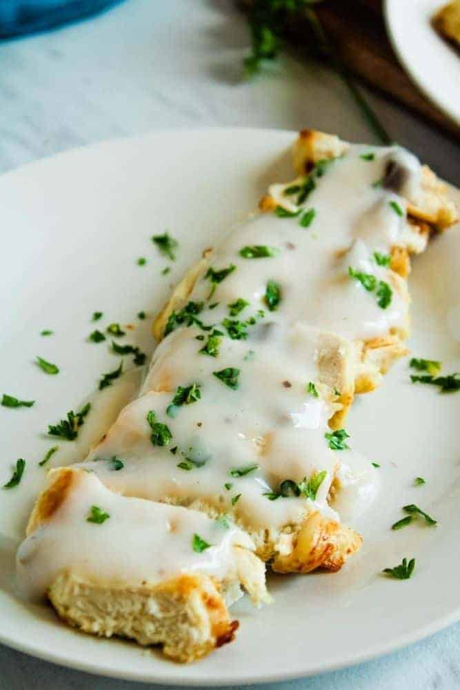 Sliced air fryer turkey on a white plate covered in mushroom sauce