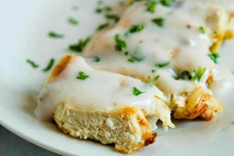 Closeup of sliced air fryer turkey steaks on a white plate with mushroom sauce