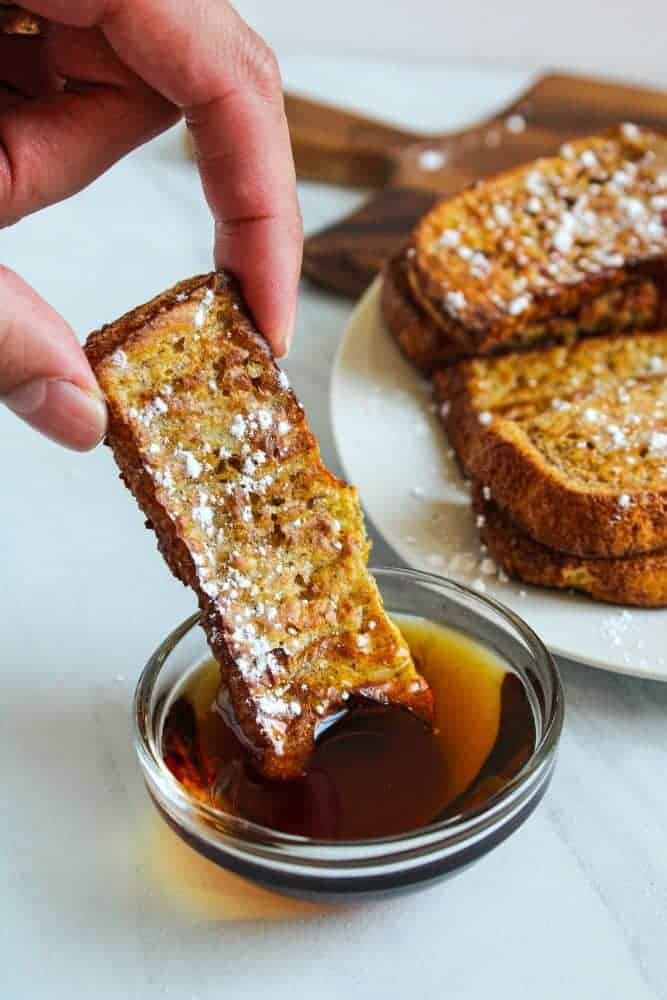 Air Fryer French Toast Stick being dipped into maple syrup