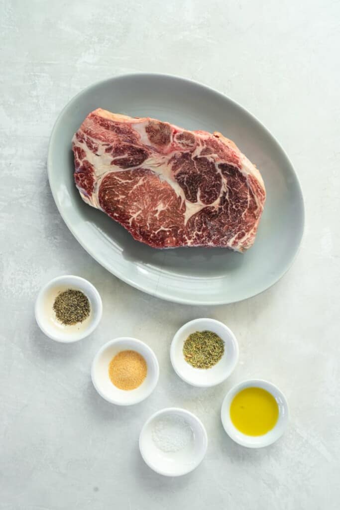 Frozen ribeye steak with other ingredients in bowls.