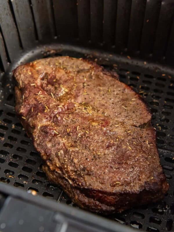 Closeup of cooked frozen steak in air fryer basket