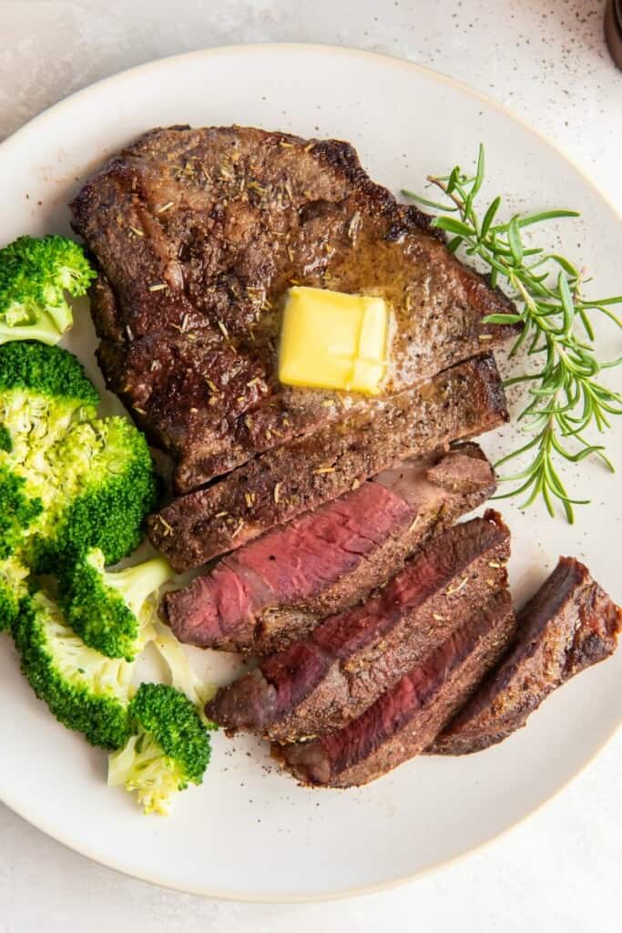 Cooked air fryer steak on a plate with half cut into slices