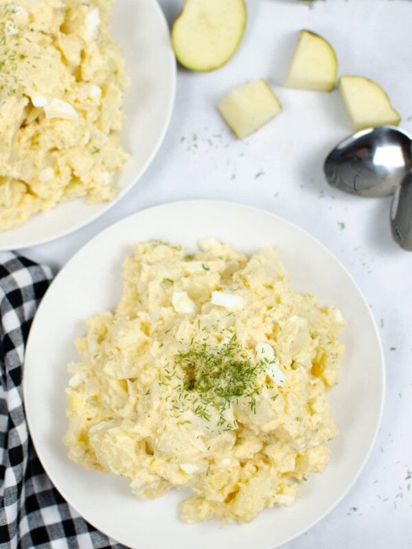 Instant Pot Potato Salad on a white plate with garnish on top and a black and white plaid napkin to side
