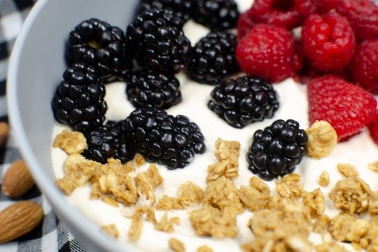 Closeup of almond yogurt in a grey bowl with berreis and granola