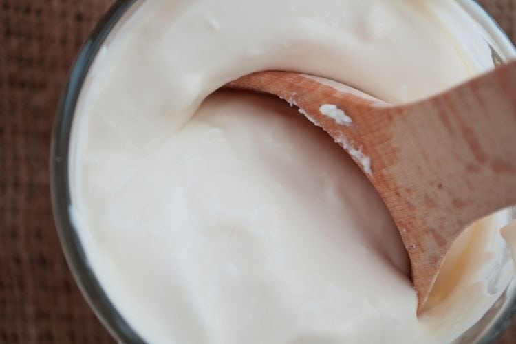 Instant Pot Almond Yogurt in container with wooden spoon