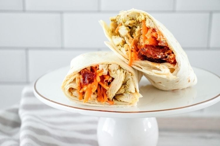 Pesto Chicken Wrap sliced in half on a white plate