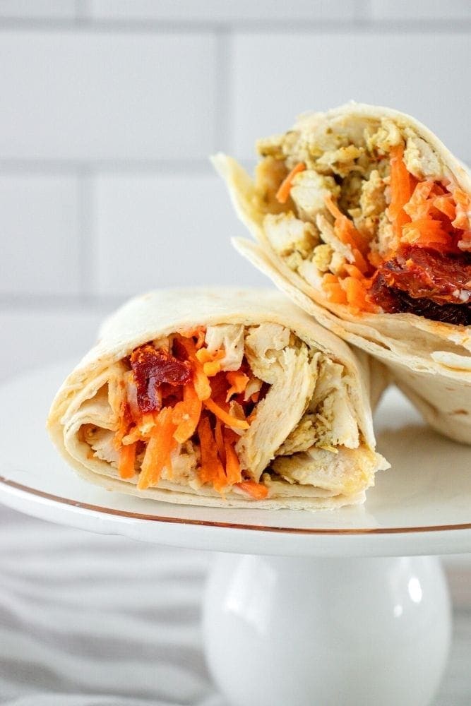 Chicken wrap sliced in half on a whie plate
