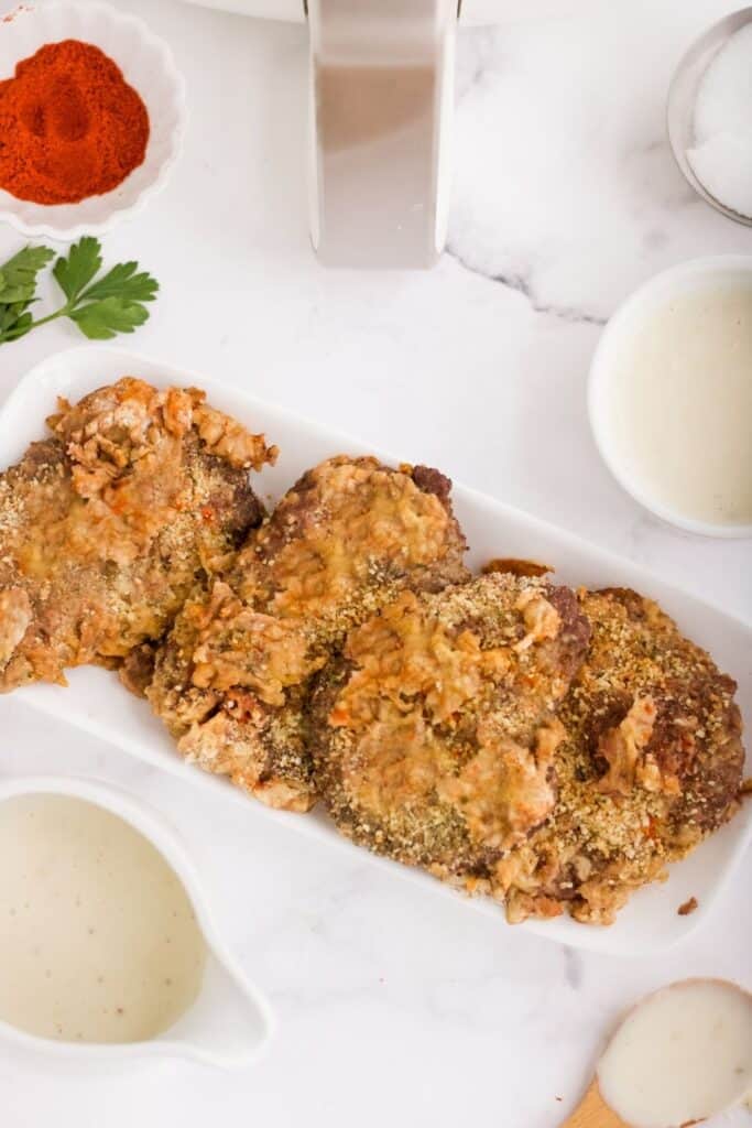 Country Fried Steak served on a long white platter plate with ingredients and air fryer around it