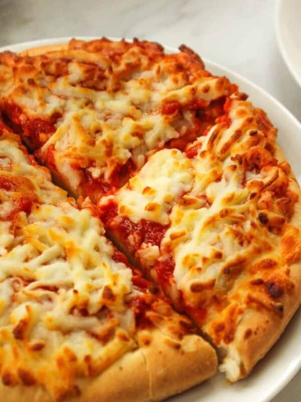 Air Fryer Frozen Pizza cut into four slices on a white plate