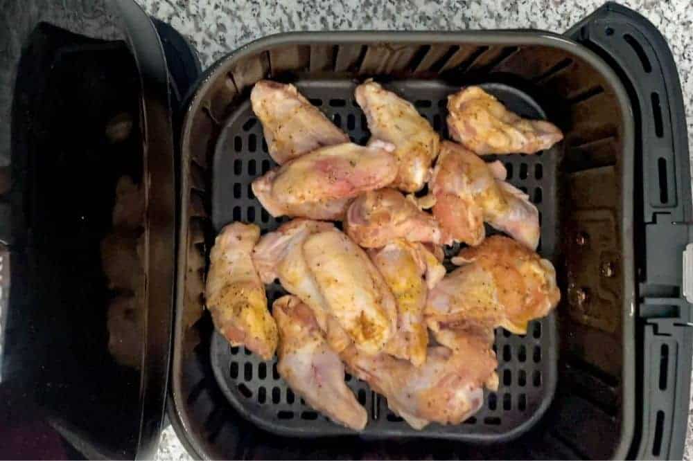 Raw chicken wings in air fryer basket