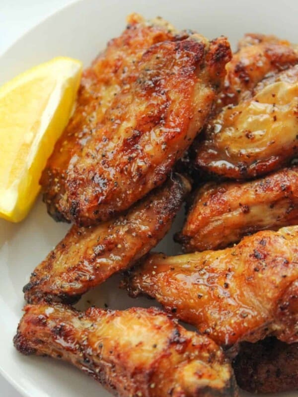 Air Fryer Lemon Pepper Wings on a white plate with a lemon slice