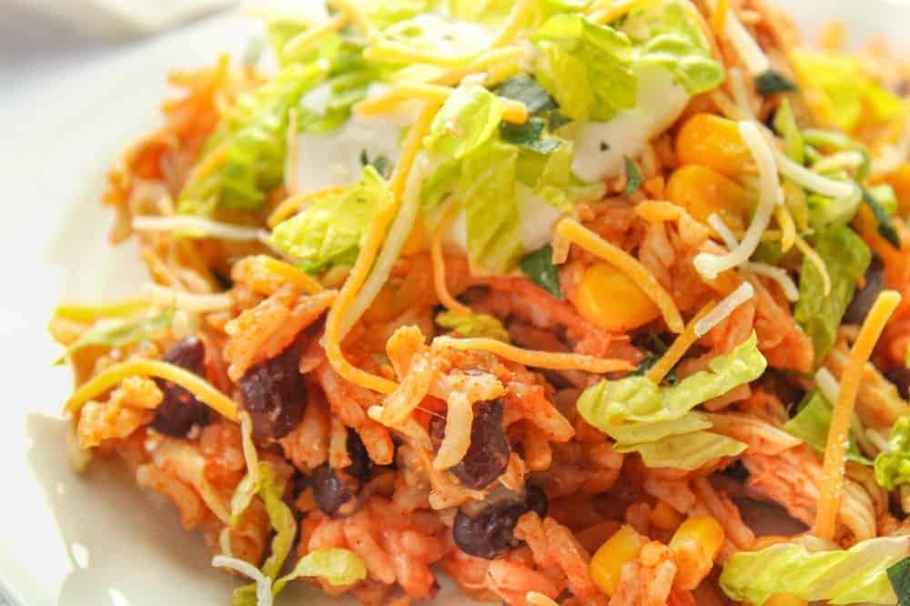 Closeup of Instant Pot Chicken Taco Bowls with lettuce, sour cream, and cheese on top in a white shallow bowl