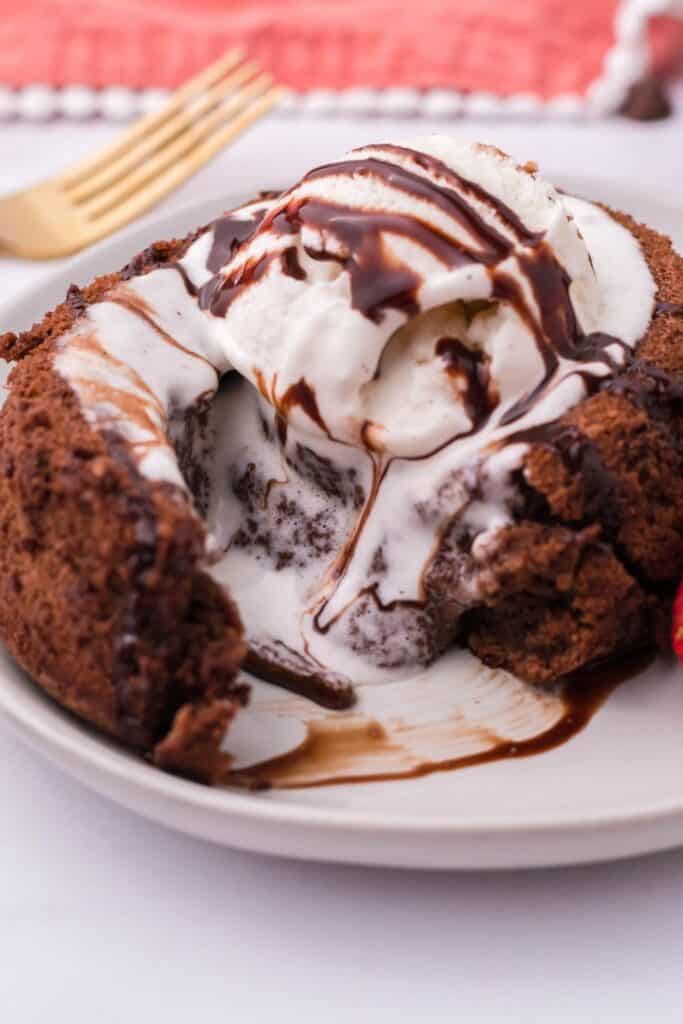Closeup of air fryer chocolate lava cake with vanilla ice cream and chocolate syrup on top