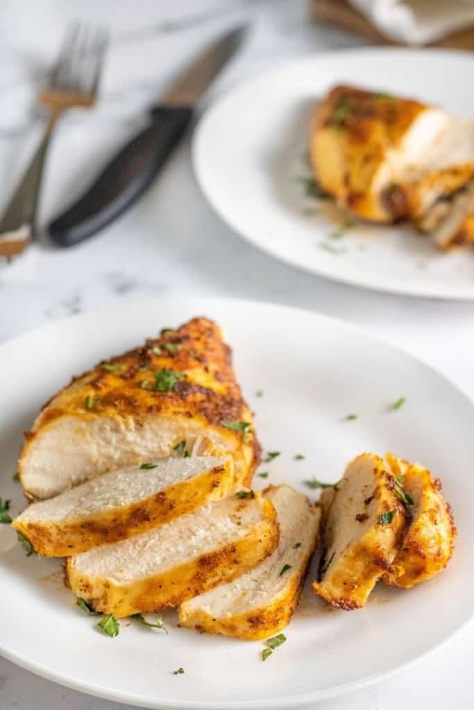 Cooked air fryer frozen chicken sliced on a plate and garnished with parsley