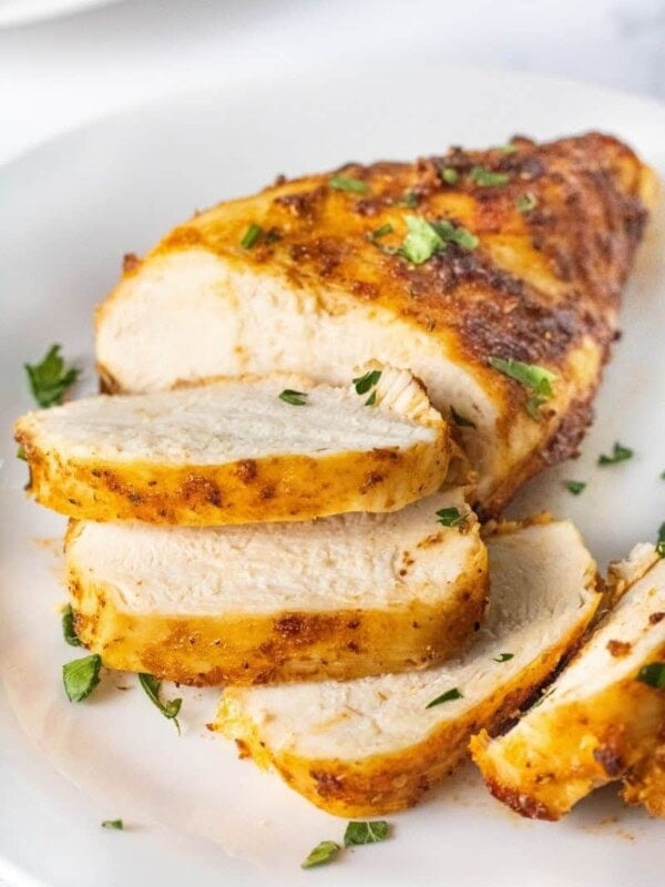 Closeup of sliced air fryer chicken breasts that were cooked from chicken on a white plate