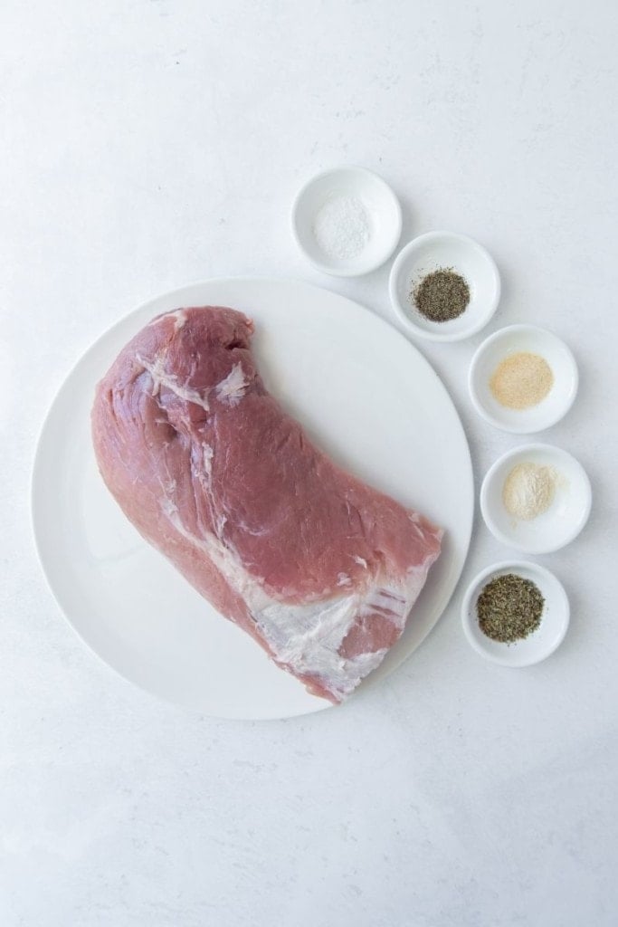 Ingredients needed to make pork loin in the air fryer on a white plate and small white bowls