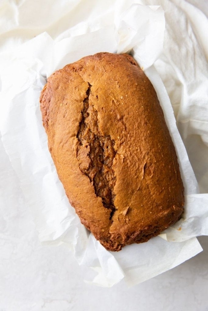 Overhead picture of finished pumpkin bread in a loaf pan with parchment paper under it
