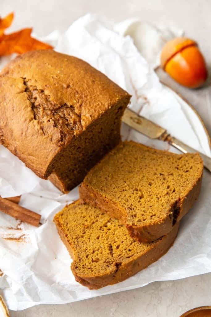 Cake mix pumpkin bread loaf with 2 slices cut laying on parchment paper