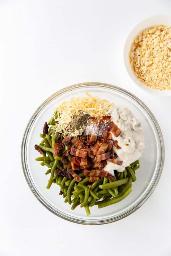 Green Bean Casserole ingredients in a bowl with ritz cracker crumbs in a bowl on the side