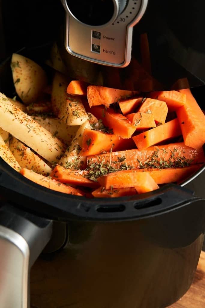 Small air fryer filled with carrots and potatoes