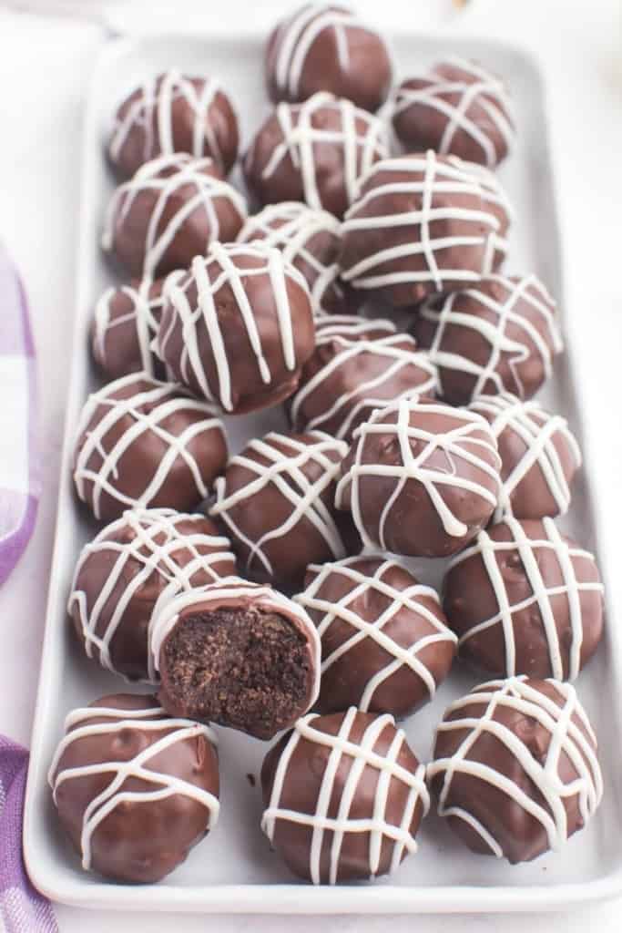 Oreo truffles without cream cheese plated on a rectangular serving plate with one that has been bitten into