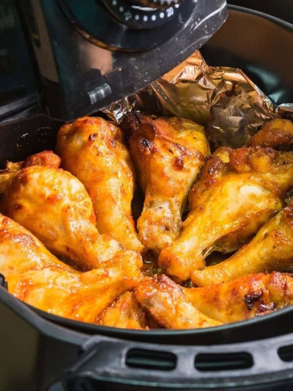 Wings being reheated in the air fryer with sauce on them and aluminum foil underneath