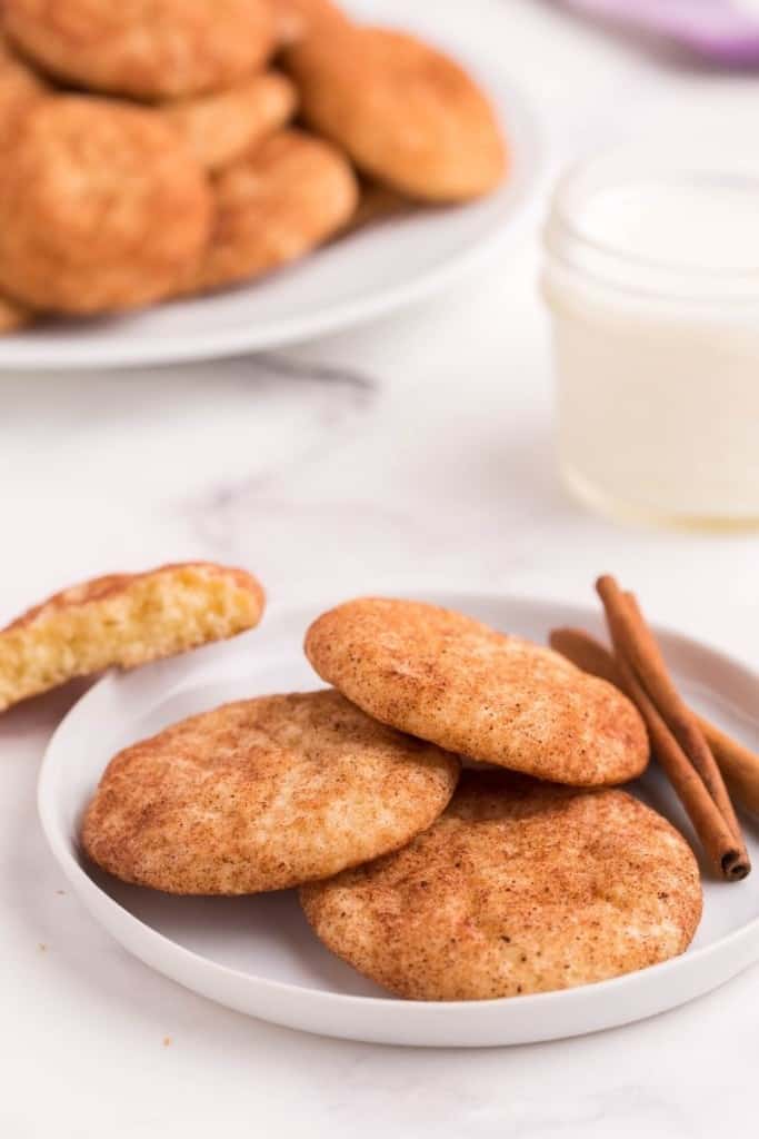 Snickerdoodle cookies on a white round plate with cinnamon sticks