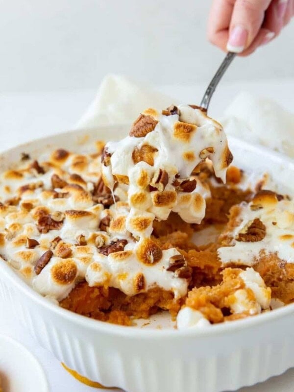 Sweet Potato Casserole with a hand pulling a serving spoon piece out