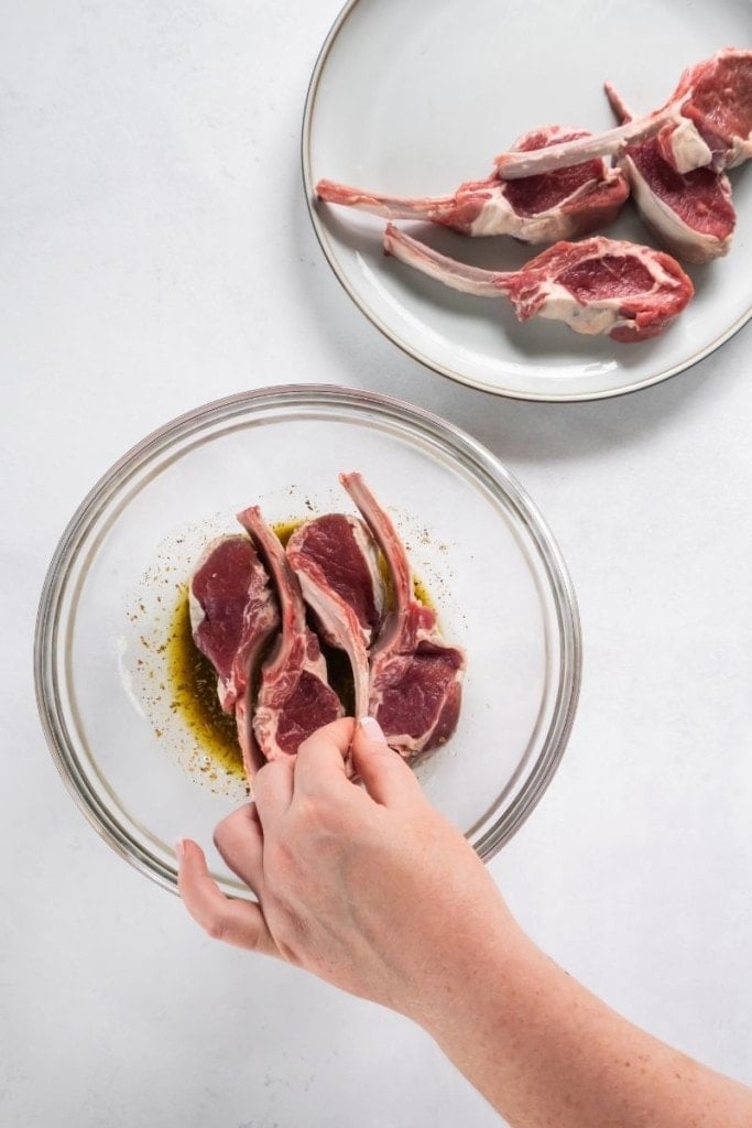 Lamb chops being placed into marinade in a bowl