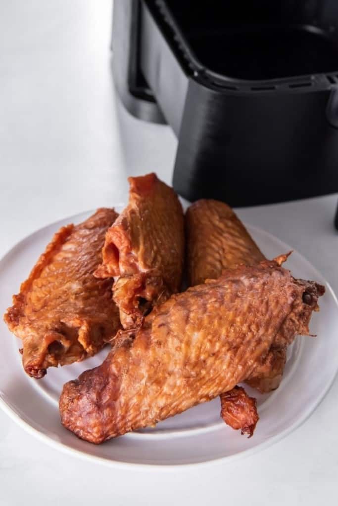 Raw pre smoked turkey wings in front of an air fryer