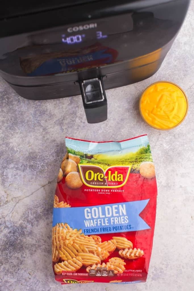 Ore Idea Golden Waffle Fries bag in front of an air fryer with a bowl of nacho cheese