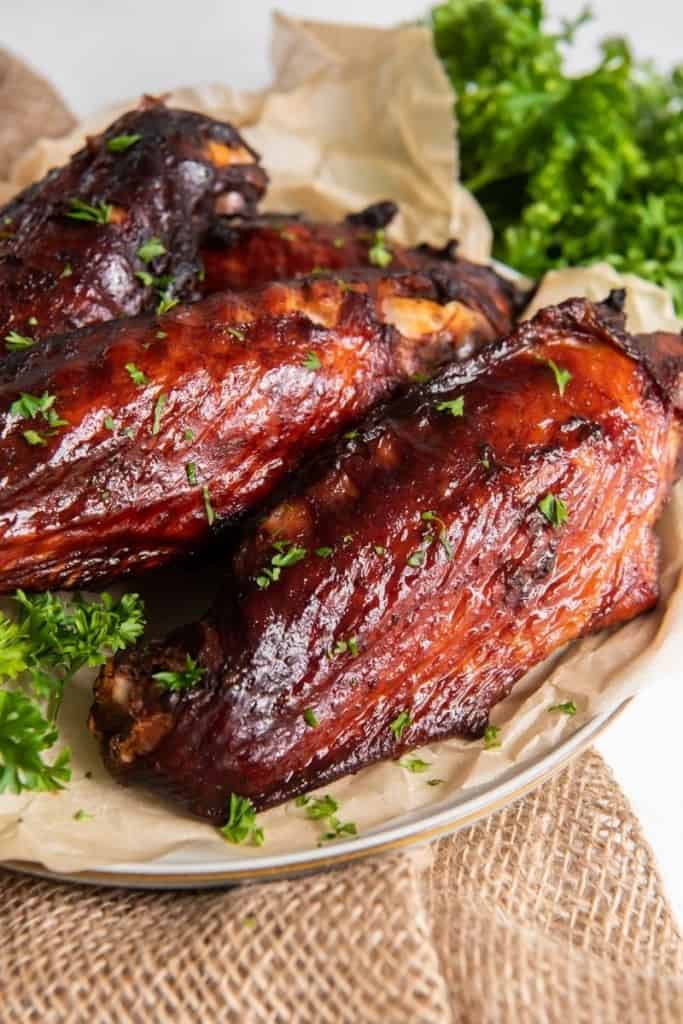 Air Fryer Turkey Wings served on a white plate with parchment paper underneath them