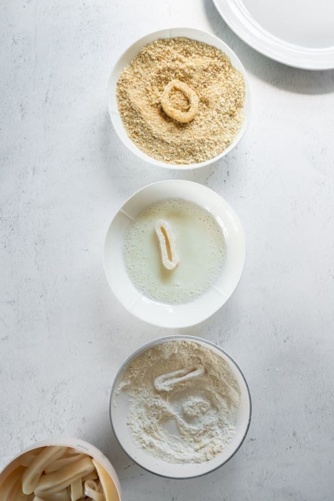 3 bowls for dipping station with raw calamari rings being dipped into each