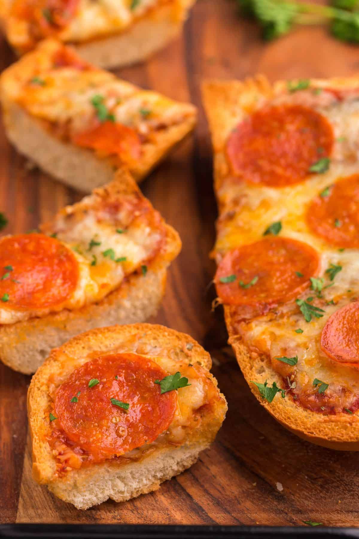 Side view of the air fry french bread pizza with one whole half and one cut into thick slices.