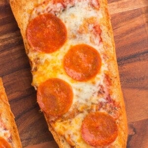 Air fryer french bread pizza with pepperoni on a wooden serving tray.