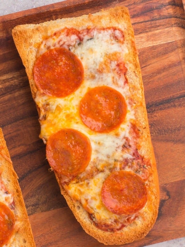 Air fryer french bread pizza with pepperoni on a wooden serving tray.