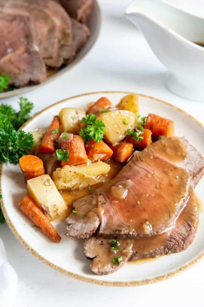 Closeup of served thin sliced Instant Pot sirloin tip roast with vegetables on a plate