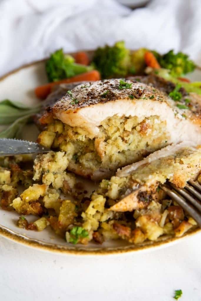 Closeup of stuffed pork on a plate sliced in half to see the stuffing inside