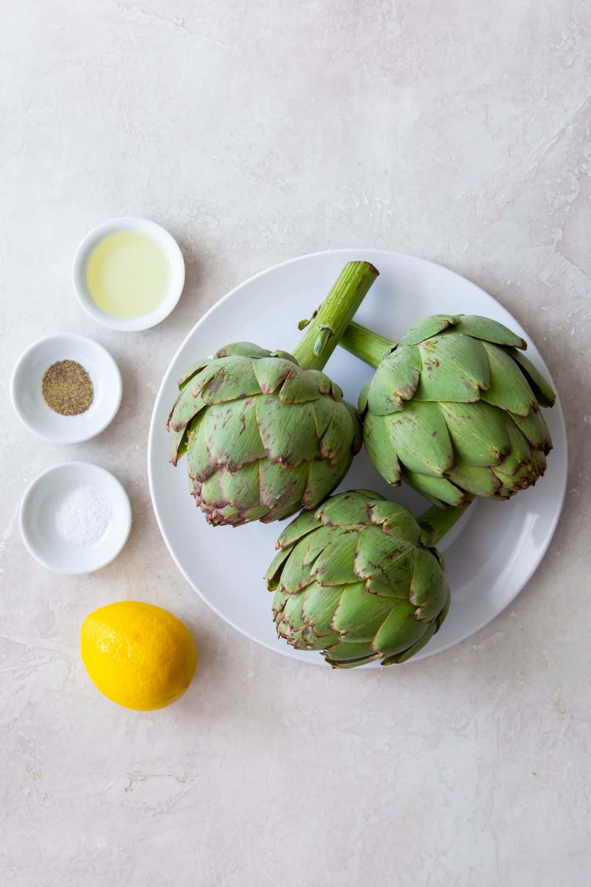 Ingredients needed to make an air fryer artichoke: artichoke, lemon, salt, pepper, and oil.